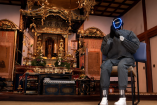 Monje robot humanoide con máscara luminosa sentado frente a un altar budista dorado en un templo de Kioto, durante la presentación de Buddharoid, un sistema con inteligencia artificial diseñado para ofrecer orientación espiritual.