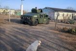 Vehículo táctico del Ejército Mexicano con un elemento armado en la torreta, estacionado en una zona habitacional rural del ejido Sandoval, en Matamoros, Tamaulipas, durante un operativo federal; en primer plano se observa un perro sentado sobre el camino de terracería.