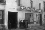 Entrada del antiguo edificio de Excélsior con letrero del diario sobre el balcón y varios hombres reunidos frente a la fachada en una calle del centro.