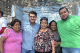 Irugami Perea Cruz posa junto a cuatro habitantes frente a una vivienda de ladrillo en una colonia de Acapulco durante una visita comunitaria.