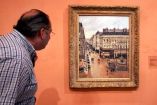 Un visitante observa el cuadro "Rue St.-Honore, Apres-Midi, Effet de Pluie" pintado en 1897 por Camille Pissarro, en el Museo Thyssen-Bornemisza. Foto: AP