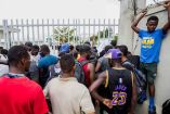 Los migrantes haitianos que fueron sacados de Texas por las autoridades estadounidenses esperan fuera del Aeropuerto Internacional Toussaint Louverture para ser procesados ​​por las autoridades haitianas