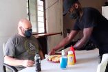 Dexter, propietario del restaurante haitiano 'Creole' sirviendo uno de sus platillos a Carlos Reséndiz, uno de sus clientes que gusta de sus comidas. Imagen: Captura de video