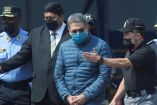 El expresidente de Honduras, Juan Orlando Hernández, es escoltado por autoridades mientras camina hacia un avión de la Administración para el Control de Drogas (DEA). Foto: AFP