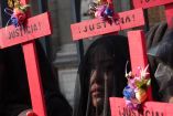 Mujeres cargando cruces rojas con nombres de víctimas de feminicidio. 