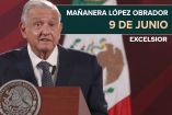 AMLO de traje y corbata en una de sus conferencias con la bandera de México al fondo