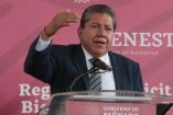 David Monreal, gobernador de Zacatecas, con traje y corbata alzando la mano derecha