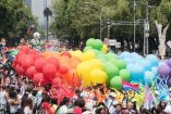 Globos arcoíris y decenas de personas congregadas en la calle por Marcha del Orgullo. 