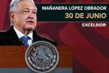 AMLO con traje y corbata sonriendo en su conferencia