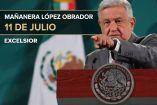 AMLO con traje gris y serio señalando con la mano izquierda y al fondo la bandera de México