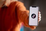 Hombre sostiene teléfono con el logo de tiktok