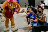 Un niño saluda a una botarga de Paw Patrol durante su vacunación contra covid-19.