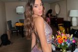 Danna Paola de espaldas con vestido brilante en una habitación flores a un costado
