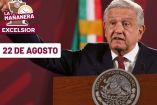 AMLO, de traje negro y corbata roja, hablando y detrás de él la bandera de México 