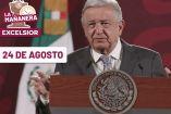 AMLO vestido con traje gris, hablando y al fondo la bandera de México