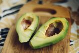 Aguacate partido sobre tabla de madera en una cocina