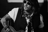Johnny Depp con guitarra en manos, lentes y mascada; foto en blanco y negro