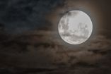 Luna llena en cielo oscuro con nubes alrededor y enfrente