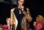 Snoop Dogg con saco dorado, botella en la mano y fumando puro