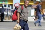 Un hombre camina con una bolsa de bolillos en su mano