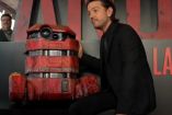 Diego Luna con traje negro junto a droide color rojo y letras de ANDOR atrás