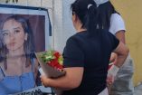 Dos mujeres, una de ellas con flores, frente a una pancarta de Debanhi Escobar