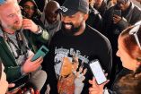 Kanye West sonriendo con playera negra estampada con imagen de Juan Pablo II