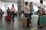 Pasajeros con sus maletas y cubrebocas en un aeropuerto