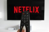 Imagen de una pantalla con el logo de Netflix y en primer plano un control