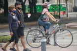 Mujer en bicicleta y pareja de adultos caminando 