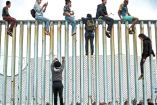 migrantes sobre el muro fronterizo
