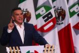 Alejandro Moreno de traje y las banderas de México y el PRI al fondo