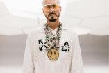 J Balvin con sudadera blanca y cadenas en el cuello; fondo blanco