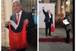 El presidente Andrés Manuel López Obrador al recibir un regalo de una asistente a su mañanera.