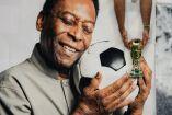 Pancarta de Pelé abrazando un balón y un aficionado le pone un trofeo