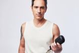 Mauricio Ochmann con camiseta blanca sin mangas y micrófono en la mano