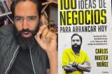 Carlos Muñoz con chaleco negro, alzando mano y libro con portada en blanco y amarillo