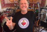 Rick Allen con playera negra haciendo símbolo de amor y paz
