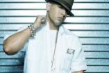 Daddy Yankee con sombrero café y camisa blanca agarrando cadena