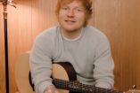 Ed Sheeran con suéter gris y guitarra entre brazos