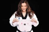María Espinoza vestida con su dobok y presumiendo una prenda de su bebé.