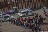 Migrantes en el muro fronterizo