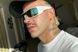 Feid de perfil con lentes blancos y gorra negra
