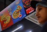 Cajera de Domino's junto a la promoción de la pizza más barata del mundo. (Reuters)