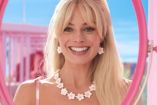 Margot Robbie sonriendo con collar de perlas en película de Barbie
