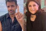 Eugenio Derbez con chaleco alzando mano y Victoria Ruffo sonriendo con traje negro