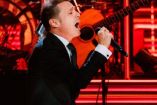 Luis Miguel cantando en concierto con micrófono en mano