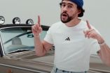 Bad Bunny con gorra azul y playera blanca recargado en Rolls Royce