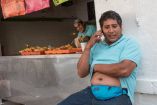 Hombre se rasca la panza mientras habla por teléfono 