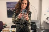 Lucero con vestido negro con brillos dorados tomándose selfie